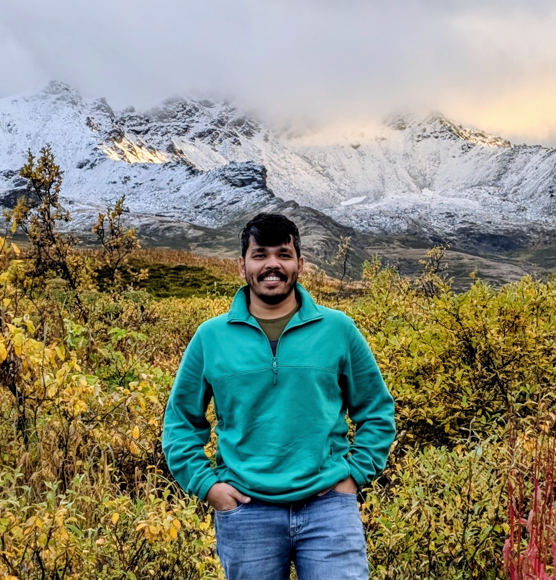 Pritesh Chauhan in front of snow-capped mountains in Alaska